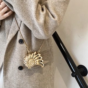 Golden nautilus shell crossbody bag with snake chain strap on model with wool coat
