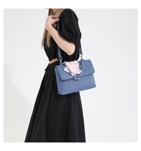 Detail of blue denim shoulder bag with pink frayed star patch and decorative chain strap
