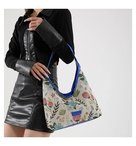 Détail d'un sac hobo en brocart floral avec des motifs vintage et bordure en cuir bleu