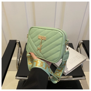 Détail du sac bandoulière vert menthe avec matelassage en V et pendentif cerf doré