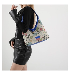 Détail du sac hobo en jacquard floral avec garniture en cuir bleu sur l'épaule
