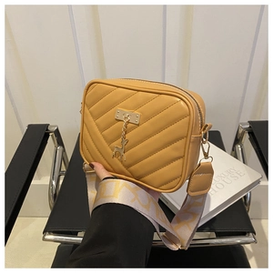 Détail du sac bandoulière jaune avec surpiqûres en V et large sangle tissée décorative