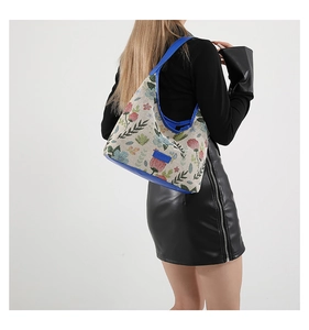 Détails de broderie sur un sac cabas en lin beige avec bandoulière bleu marine