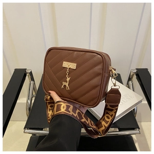 Vue détaillée d'un sac bandoulière matelassé marron avec charm cerf doré et sangle large