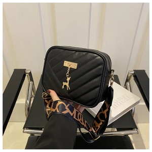 Détail du sac bandoulière matelassé noir avec breloque cerf dorée et large sangle lettrée