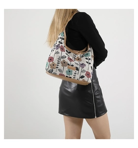 Detail of floral tapestry tote bag featuring leather base and fashion label on shoulder