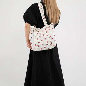 Chic corduroy tote bag with strawberry print shown on model's shoulder from behind