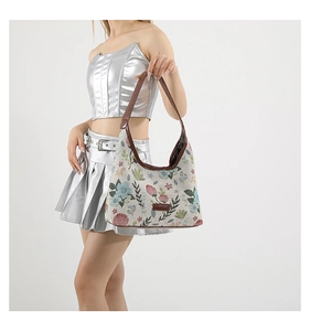 Sac à bandoulière jacquard fleuri avec sangle en cuir marron porté à l'épaule