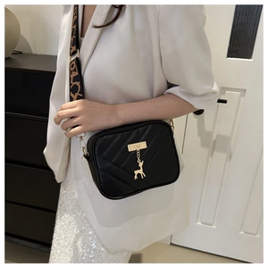 Détail du sac bandoulière noir en similicuir matelassé avec pendentif cerf doré élégant