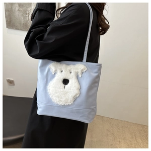 Détail du grand sac cabas bleu clair montrant le patch chiot en peluche 3D et le nylon