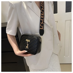 Détail du sac bandoulière matelassé noir avec breloque cerf doré et sangle jacquard