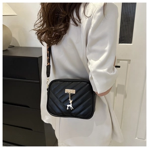 Detail of black quilted crossbody bag with golden deer charm and leopard print strap