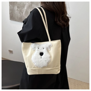 Détail d'un sac cabas beige avec écusson chien en peluche porté par un mannequin