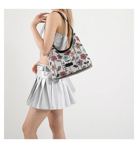 Sac fourre-tout en toile à fleurs avec bandoulière noire porté par un mannequin