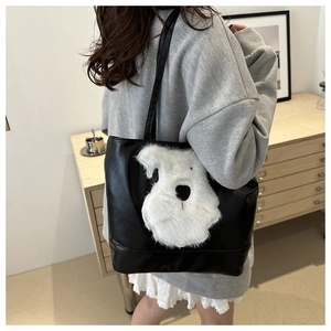 Détail d'un cabas en cuir noir avec un design mignon de chiot en peluche blanche