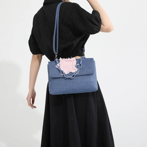 Blue denim crossbody bag featuring pink star patch and chic blue chunky chain handle