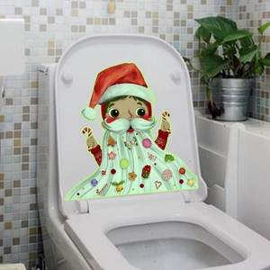 Détail d'un autocollant de gnome de Noël sur un abattant de WC avec décorations festives