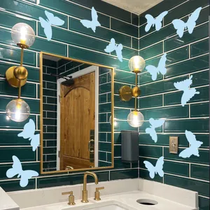 Luminous light blue butterfly wall decals displayed on dark green bathroom tile walls