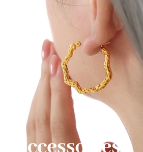 Detailed view of large gold hoop earrings with a wavy hammered texture for women
