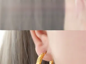Macro detail of textured hollow geometric gold earrings on a model's ear lobe