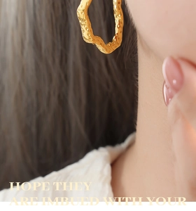 Detail of gold geometric hollow earrings with hammered texture on a model wearing them