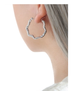 Detail of silver hollow geometric irregular wavy earrings on model for a trendy look