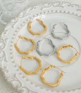 Detailed view of textured gold and silver irregular geometric earrings on a white plate