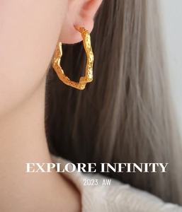 Close-up of gold-plated hollow geometric hoop earrings with hammered texture on a model