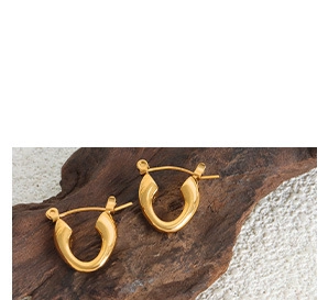 Polished gold U-shaped horseshoe earrings placed on a natural wood surface with white background