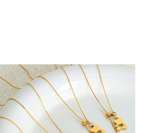 Macro shot of gold-plated bear pendant necklaces hanging on a white ceramic bowl edge