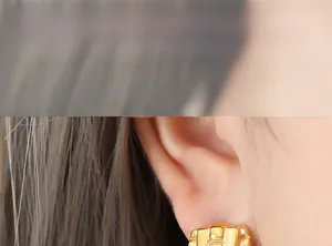 Close-up of gold woven texture earrings on ear, featuring a vintage square metal design