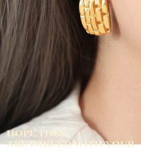 Close-up of gold geometric textured earrings worn by a model in a retro style