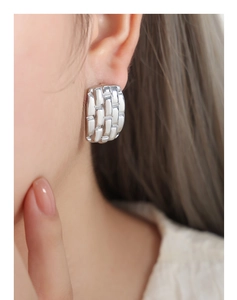 Macro detail of silver geometric square texture earring on model's ear