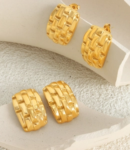 Macro shot of gold rectangular earrings with textured lattice design on stone blocks