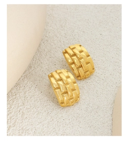 Macro detail of golden geometric textured earrings with wide woven pattern on neutral base