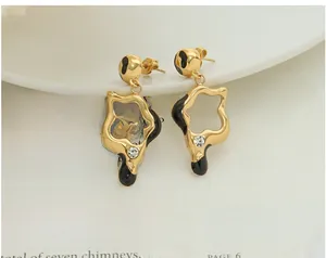 Close-up of irregular hollow star earrings with black enamel and zircons on a vintage book