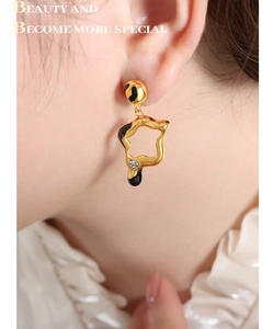 Macro shot of French style irregular gold earrings with black enamel and small diamond inlay