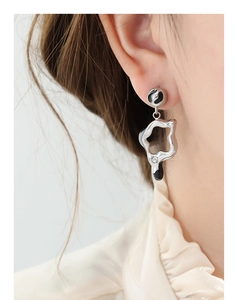 Macro view of geometric silver star earrings with black enamel and zircon inlay
