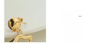 Macro shot of gold-plated geometric wavy earrings with premium black enamel detailing