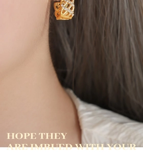 Close-up of a gold mesh earring with sparkling cubic zirconia on a female model's ear