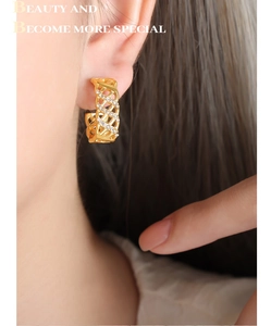 Detail of gold hollow mesh C-shape earrings with small diamonds worn on ear