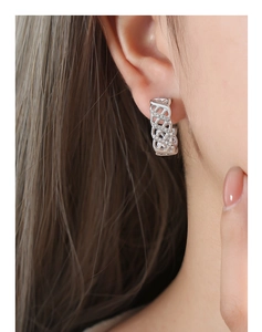 Close-up of silver mesh hollow earrings with rhinestones on a female model's ear