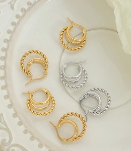 Détail de boucles d'oreilles créoles à trois couches dorées et argentées à texture torsadée
