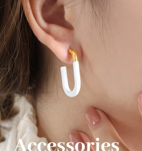 Close-up of a U-shaped gold and white enamel geometric earring worn by a model