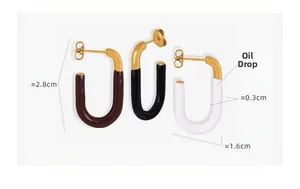 Detailed view of U-shaped enamel earrings in black, brown and white with 18k gold plating