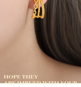 Macro shot of three-layer gold-plated C-shaped earrings with twisted and beaded textures