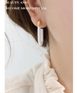 Detail of French vintage gold U-shaped earring with white enamel on a female model