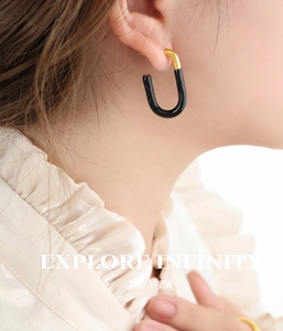 Close-up of black and gold U-shaped enamel earrings worn on model for a chic aesthetic