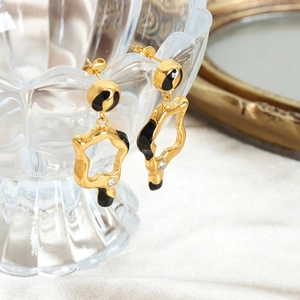 Irregular gold star earrings with black enamel and zircon on a crystal glass rim