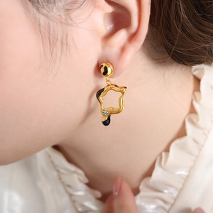 Star-shaped gold lava earrings with black enamel drip and zircon on female model